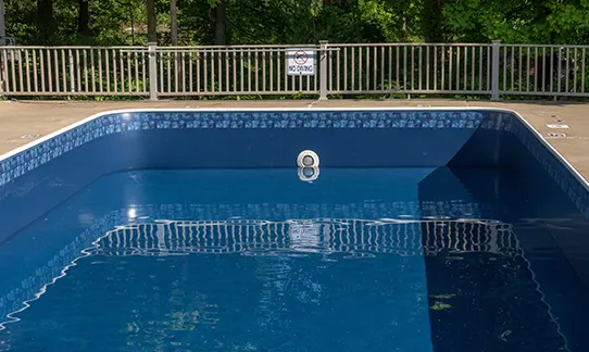 Empty residential backyard pool with blue vinyl lining and white railing
