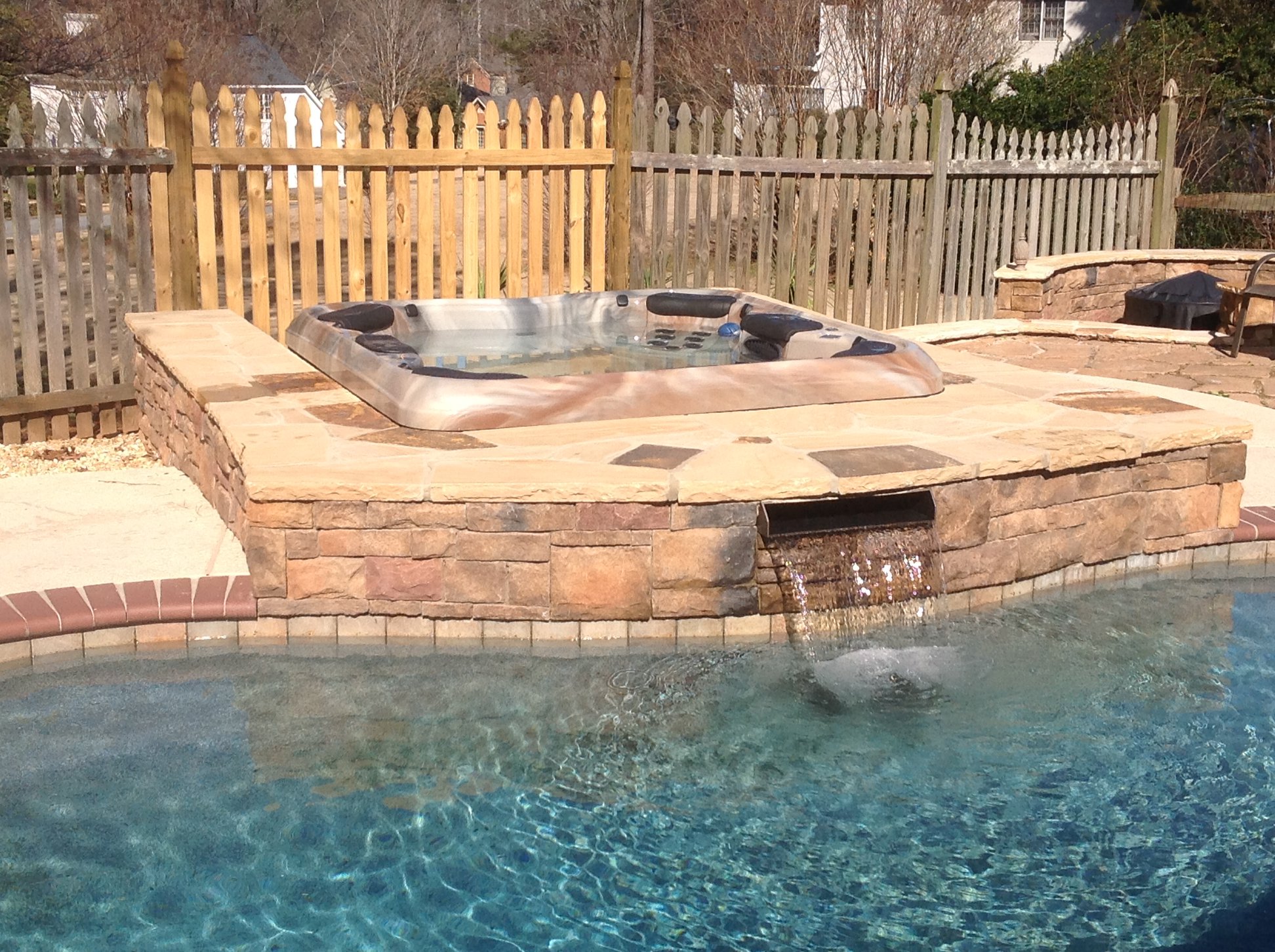 Luxurious backyard spa with waterfall feature next to residential swimming pool