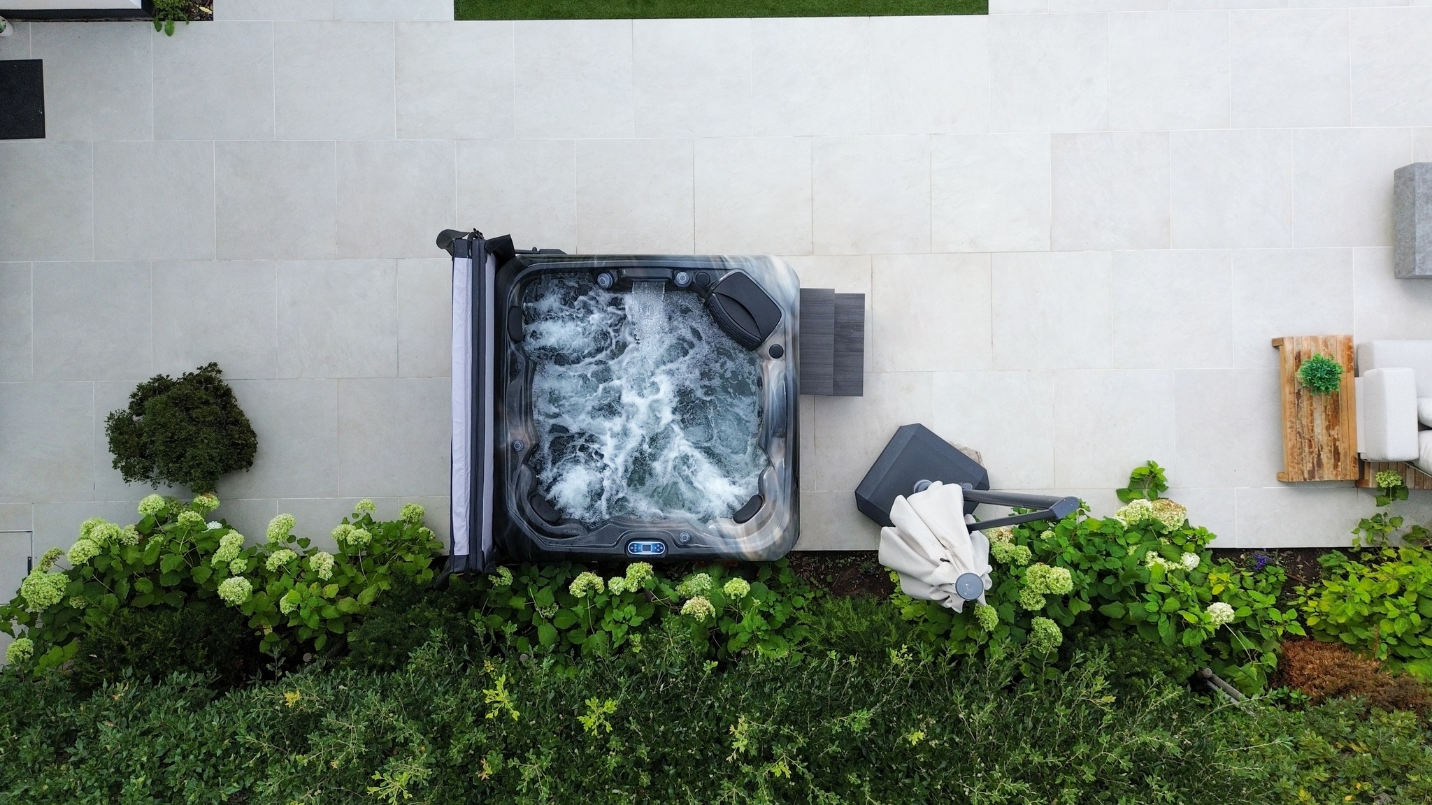 Overhead view of inflatable hot tub installed in modern backyard with landscaping and maintenance accessories