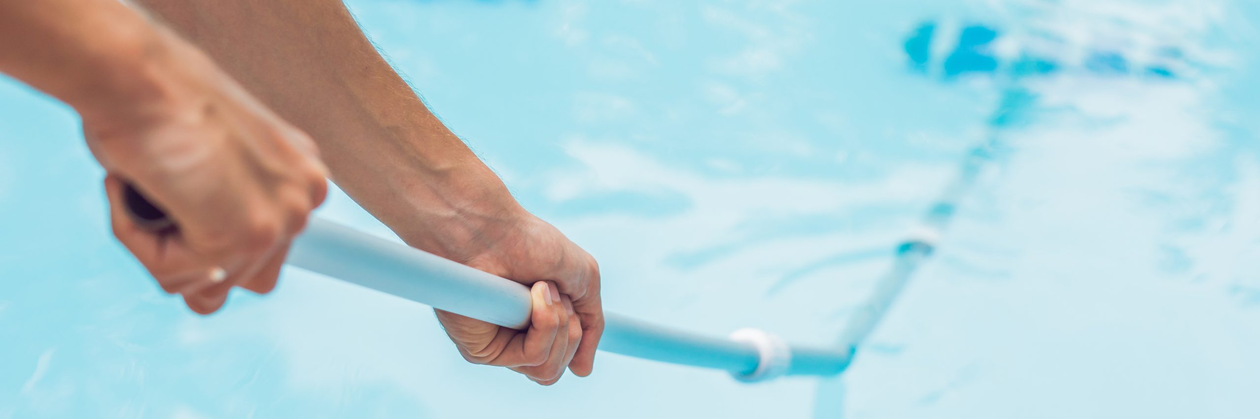 Person holding poolside railing with clear backyard pool water in background