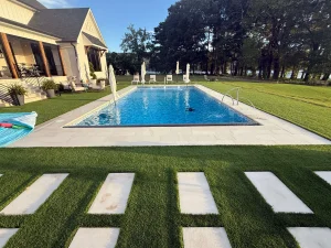 Modern backyard pool with stepping stones, umbrellas, and residential spa house