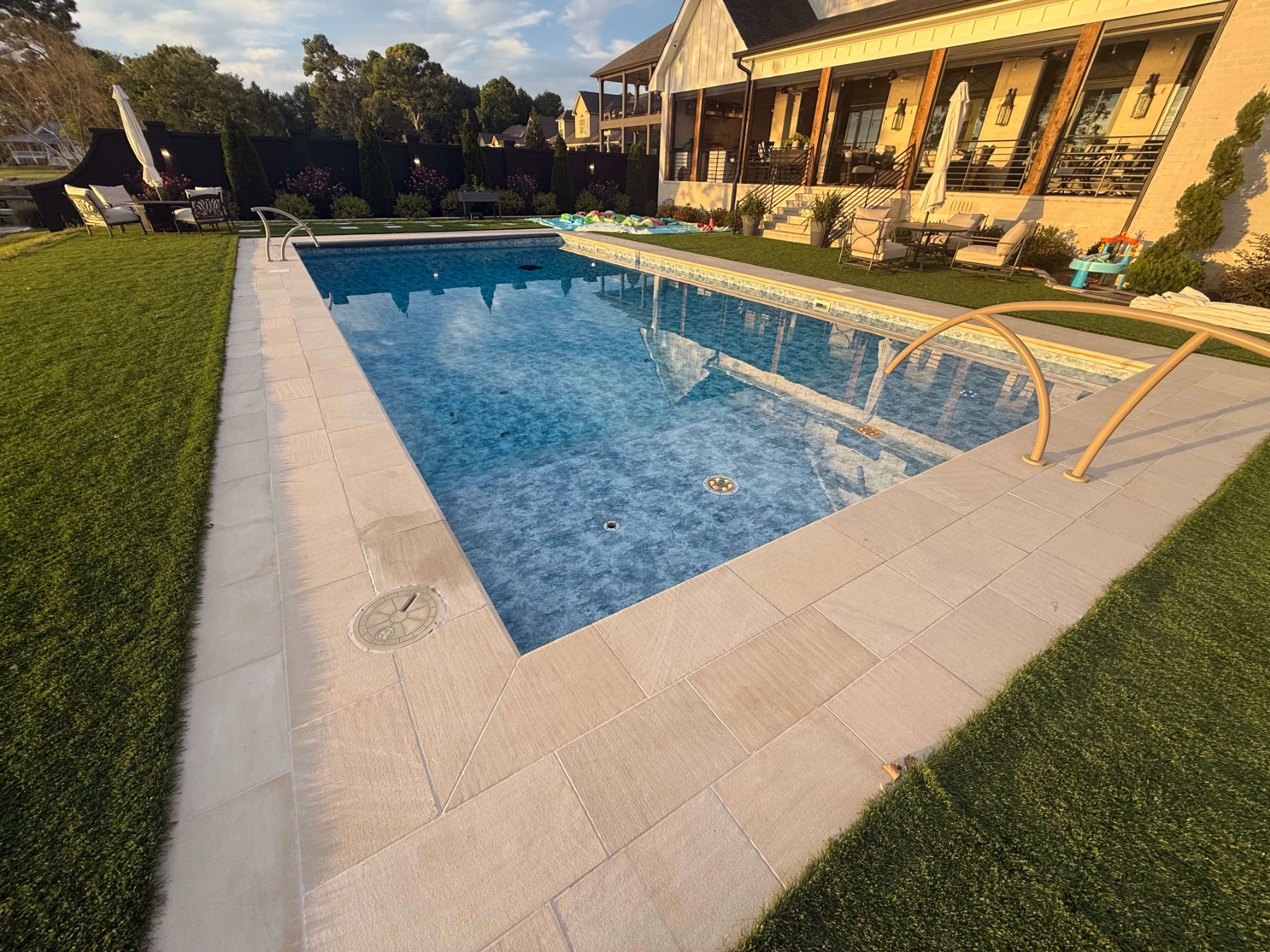 Luxurious backyard pool with lounge chairs beside yellow residential home