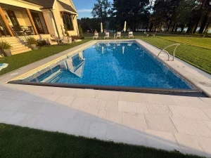 Luxurious backyard pool with lounge chairs and yellow residential home nearby