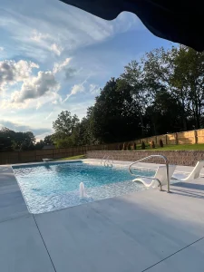 Modern residential backyard pool with lounge chairs and wooden fence enclosure